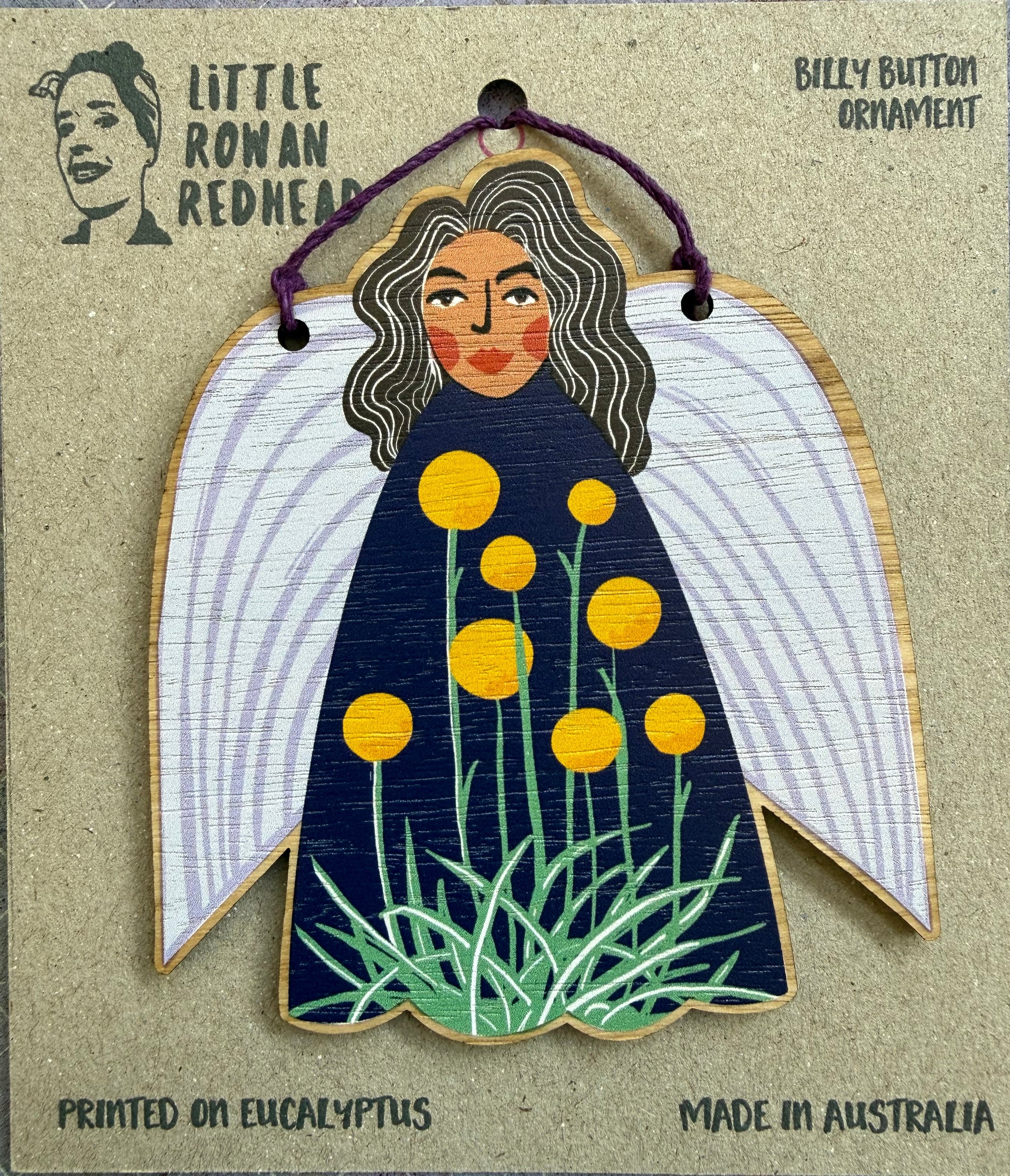 A wooden fairy ornament featuring billy button flowers