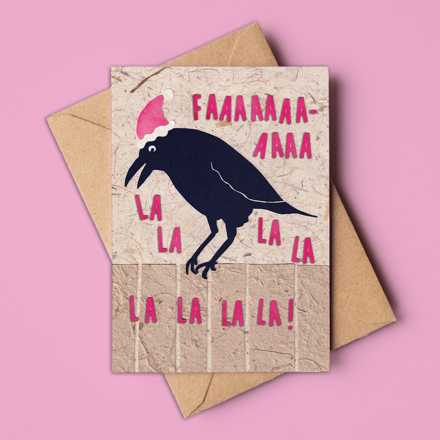 A6 Christmas card featuring a black crow wearing a Santa hat, surrounded by the text “Faaaaa-la-la-la” in bold pink letters on a textured kraft background. Includes kraft envelope. Made in Australia, wholesale available.