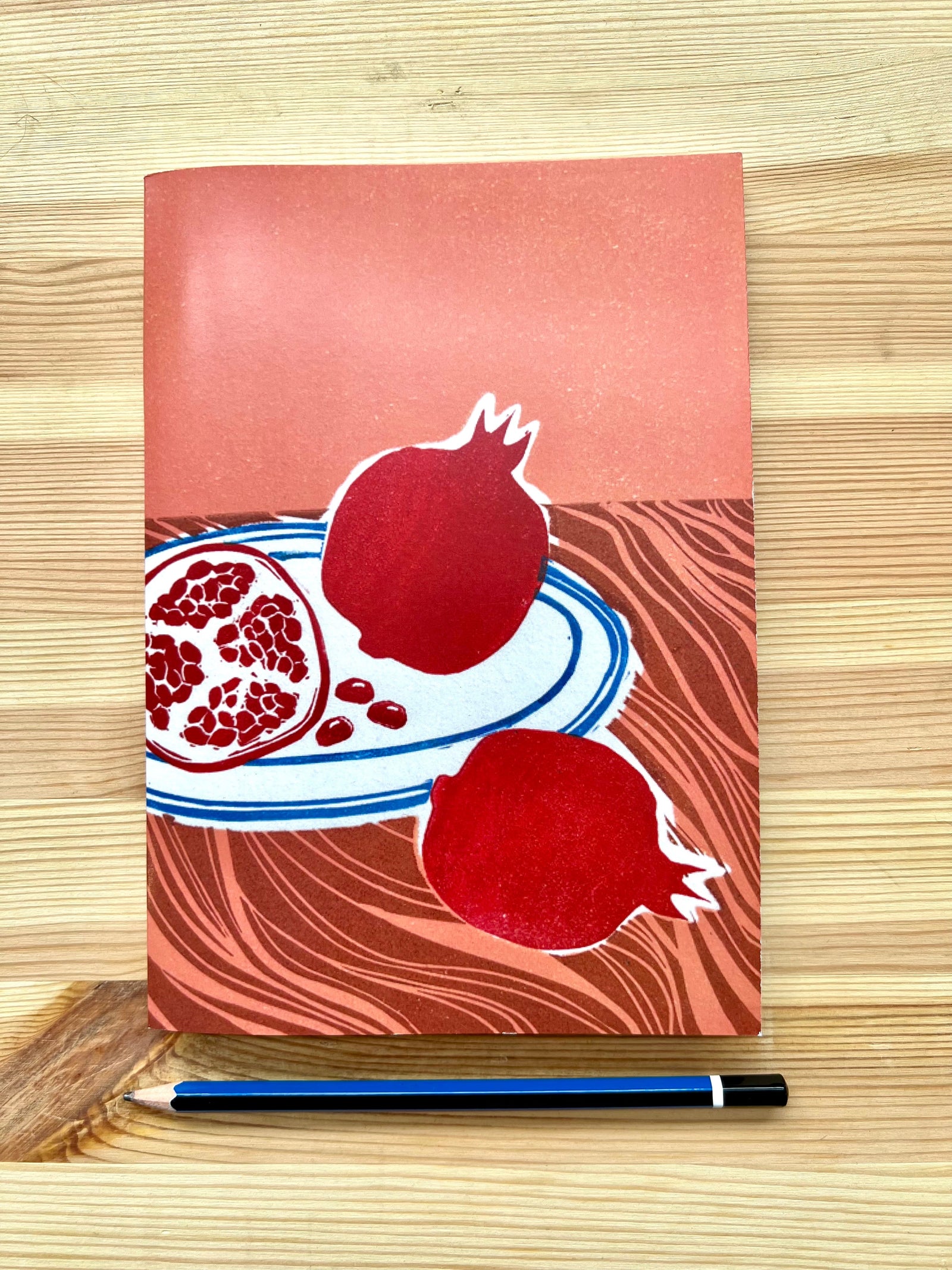 A5 lined notebook featuring a still life of pomegranates on a plate done in linoprint style, stationery made in Australia, available for wholesale