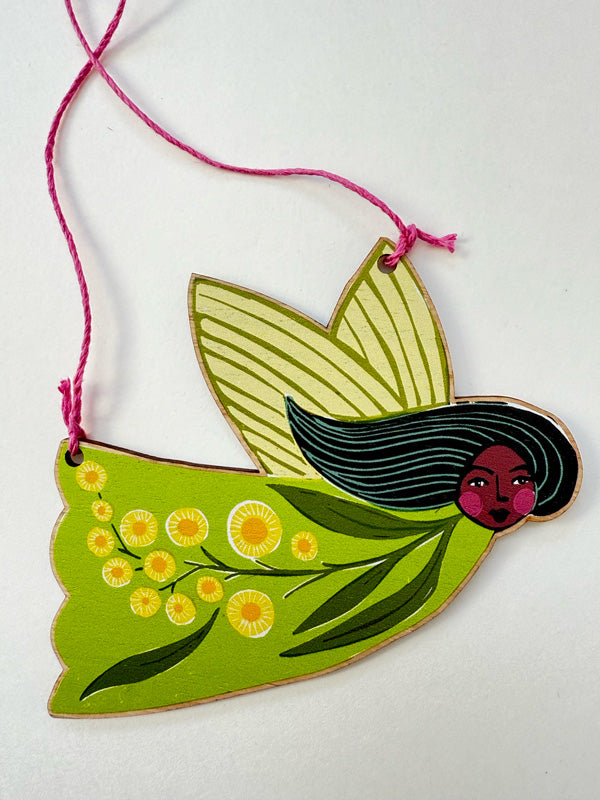 Wooden Christmas ornament made in Australia featuring a fairy decorated with native wattle flowers. Strung with colourful hemp cord. Available for wholesale. 
